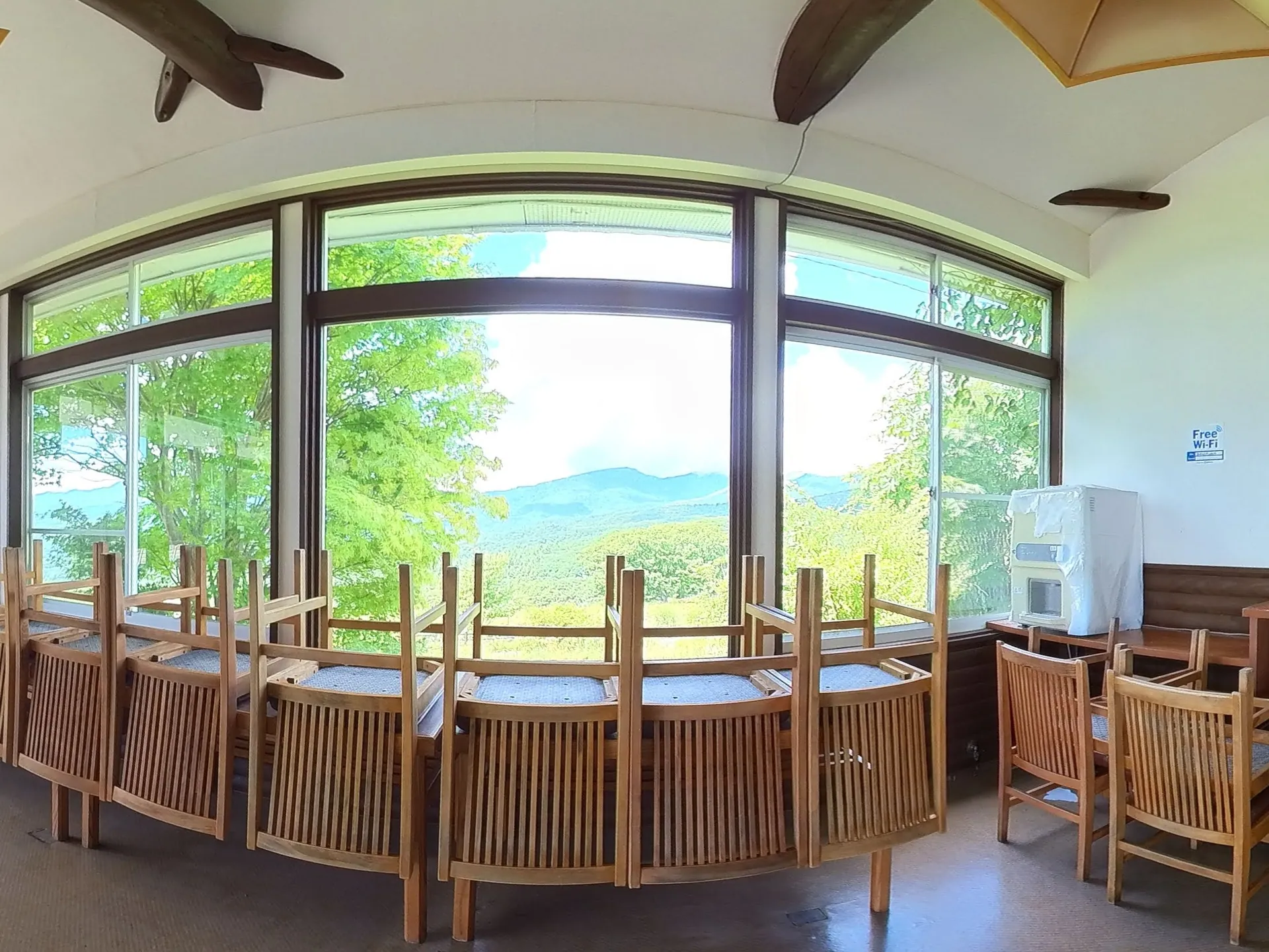 August 2025 — chairs stacked against the window wall, the mountains already framed in the glass