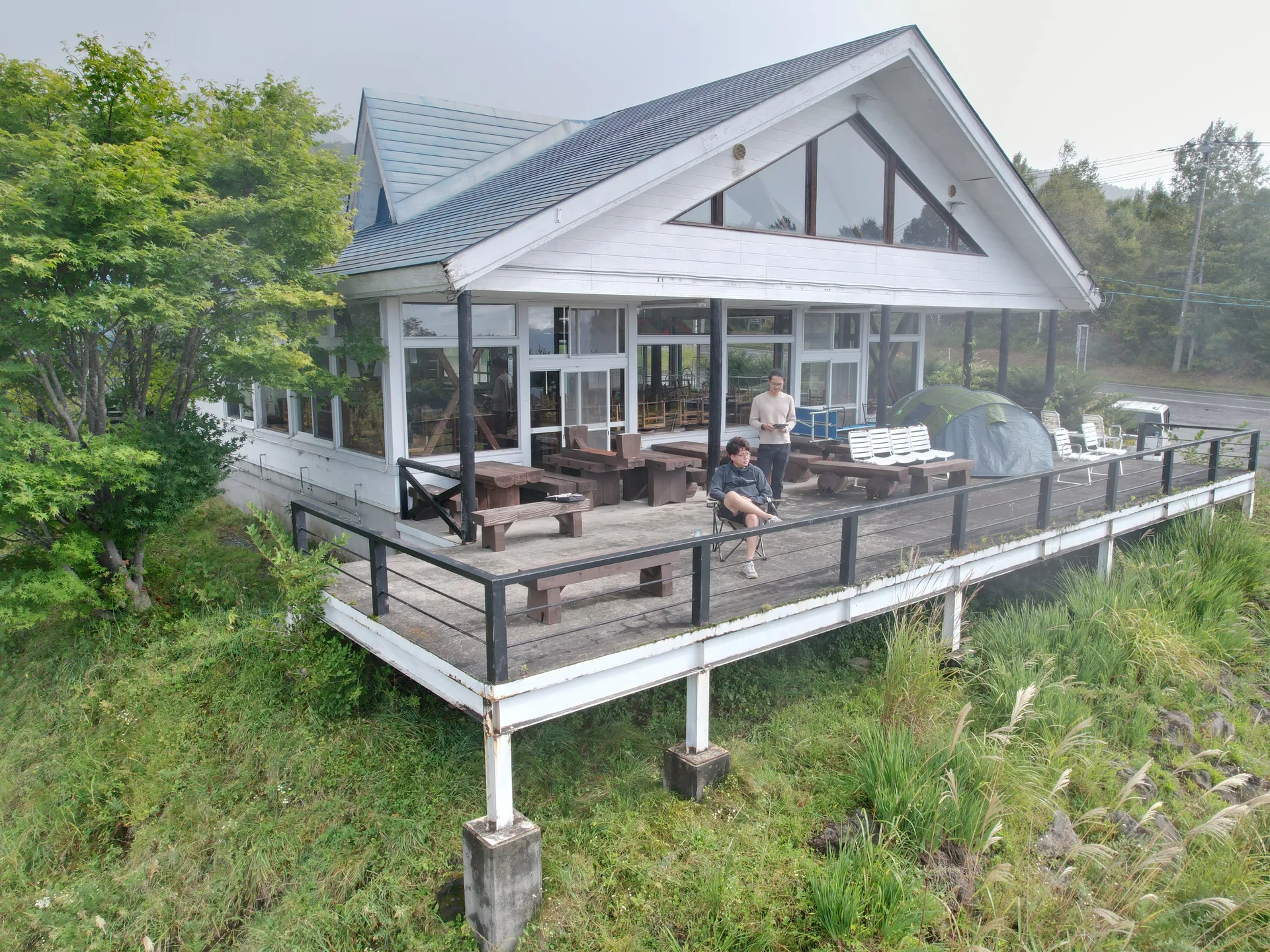 September 2025 — the hall seen from the field, grass still uncut around the deck