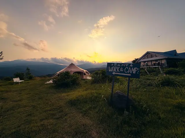 Sunset over the hall, the sign and a bell tent on the field