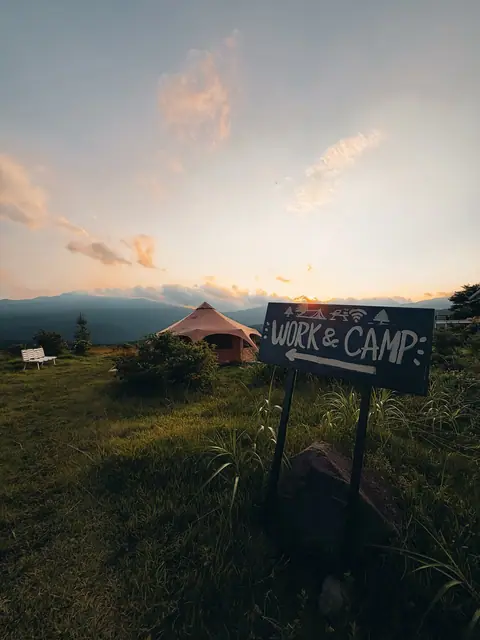 The Work&Camp sign and a bell tent on the field at sunset